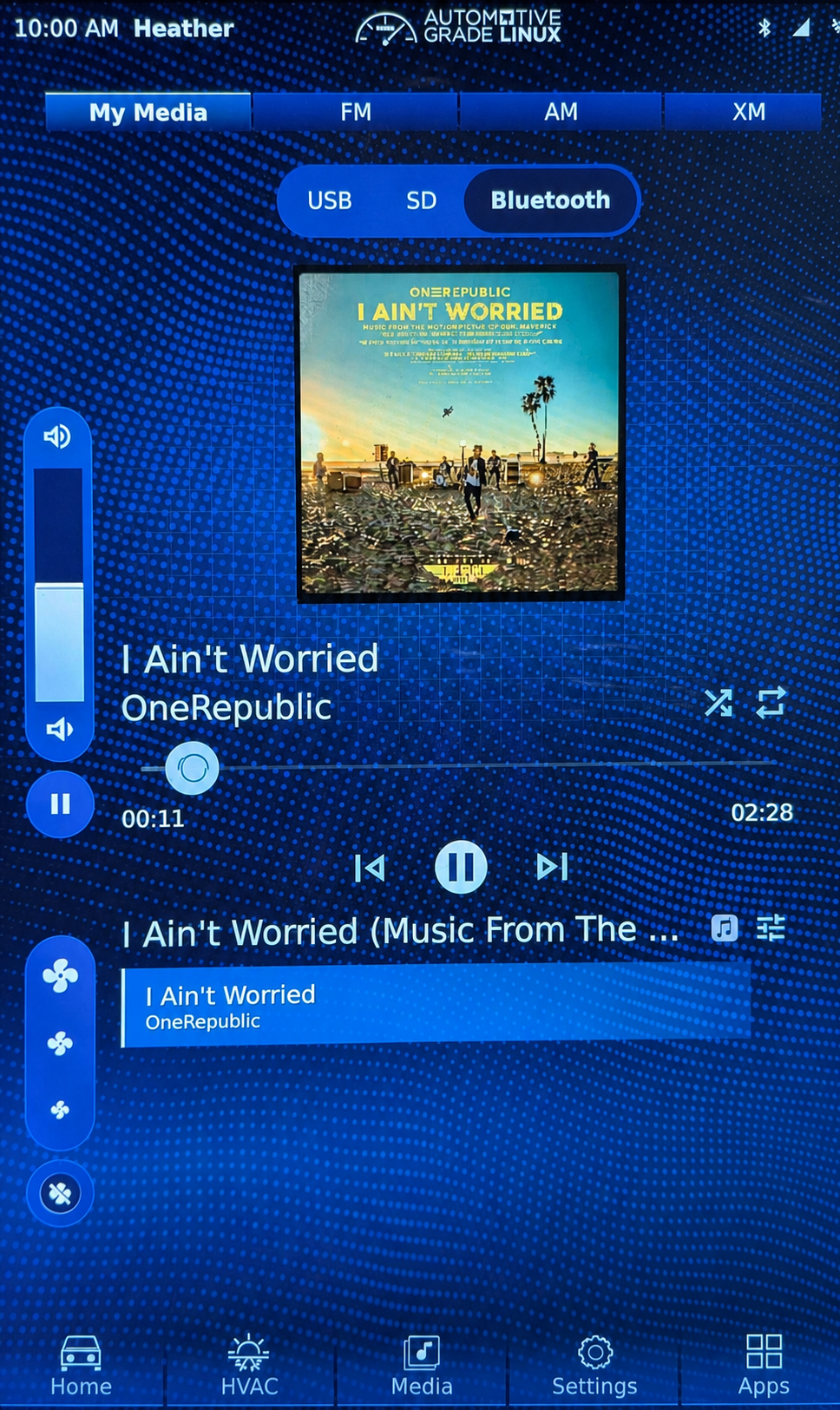 Full AGL Bluetooth media screen playing I Ain't Worried by OneRepublic with cover art, metadata, progress, playback controls, and a media item row.